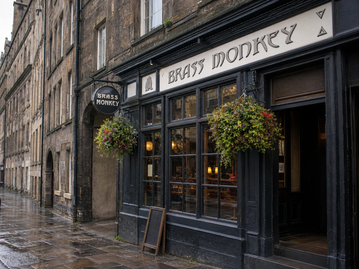 Brass Monkey’s dark Drummond Street frontage with white lettering, hanging roundel, multi-pane windows and flower baskets.