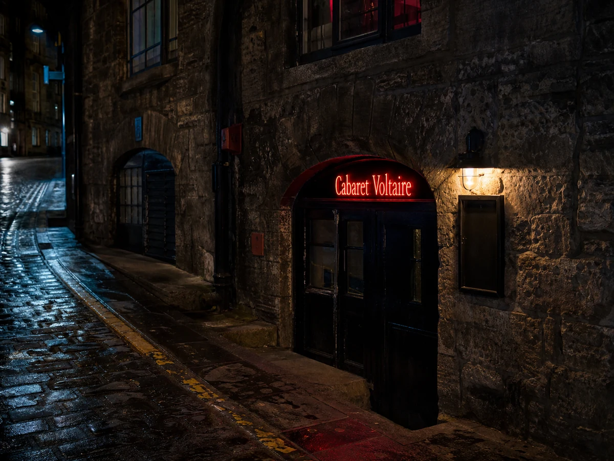 Cabaret Voltaire’s late-night Blair Street entrance in weathered Old Town stone, with a low arch and red neon identifier.
