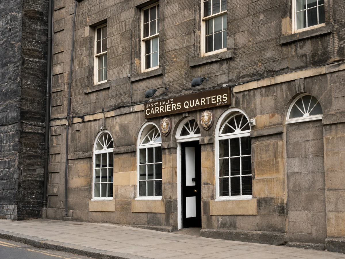 Henry Hall’s Carriers Quarters’ weathered sandstone frontage, arched fanlights and brown nameboard.