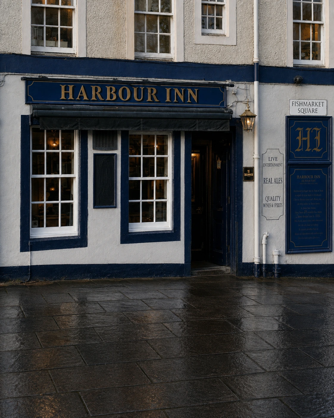 Harbour Inn’s white frontage with navy signage, four upper windows and a recessed right-hand entrance.