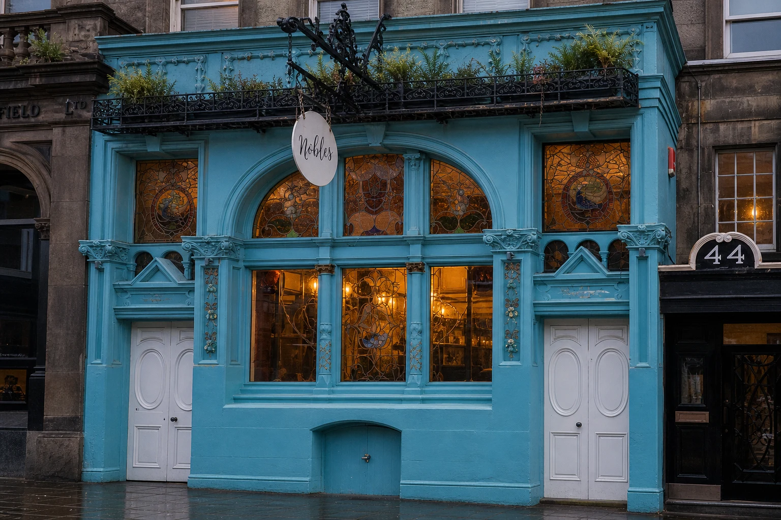 Ornate turquoise Nobles frontage on Constitution Street with arched stained glass, white doors and a clearly lettered round hanging sign.