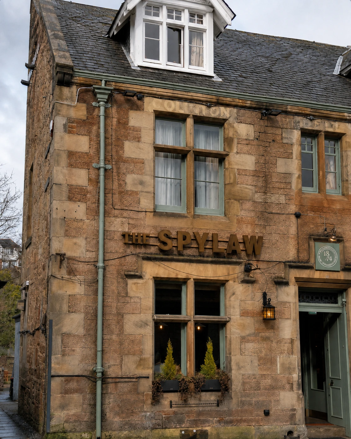 The Spylaw’s sandstone named bay with pale green joinery and a white dormer.