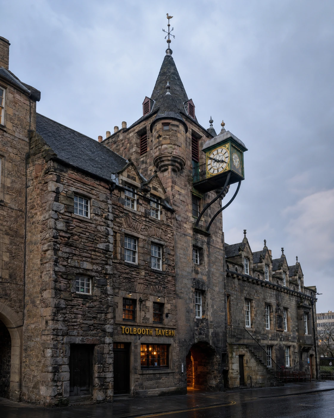 Tolbooth Tavern beneath the Canongate Tolbooth’s sandstone turret, conical spire and projecting green clock after rain.